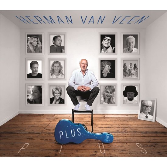 Herman van Veen zittend op een stoel voor een muur met portretten, met een blauwe gitaarkoffer waarop 'PLUS' staat.