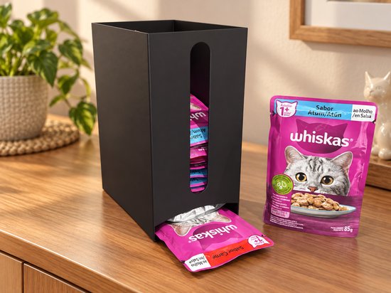 Zwarte metalen dispenser gevuld met Whiskas kattenvoerzakjes op een houten tafel.