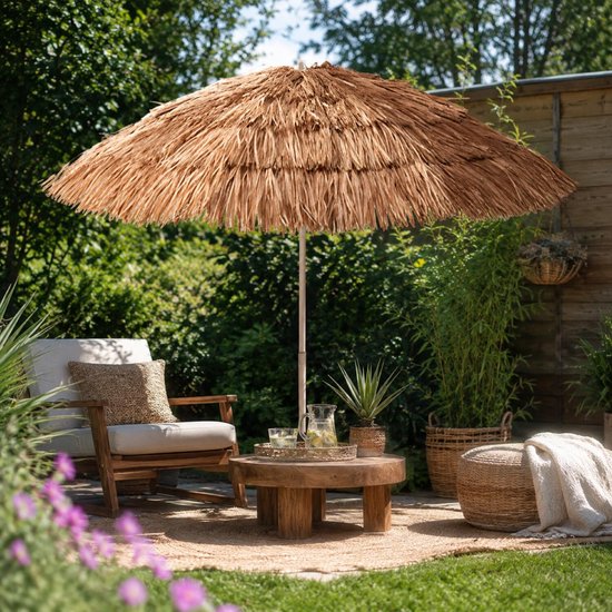 Raffia parasol bij een houten salontafel en rotan stoel op een terras.