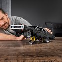 Een man tilt een zwarte Lego Charger op een krik.