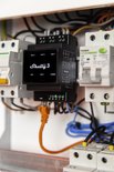 Zwart Shelly Pro 3 DIN-railrelais in meterkast met bedrading, een oranje LAN-kabel en indicatieaanduidingen.