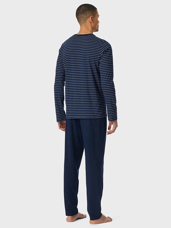 Man van achteren gezien in een marineblauwe pyjamaset met gestreept bovenstuk en effen broek.