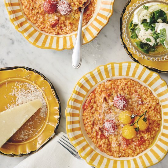 Deux assiettes de risotto orange aux tomates et au parmesan, servies dans des assiettes jaunes à rayures blanches.
