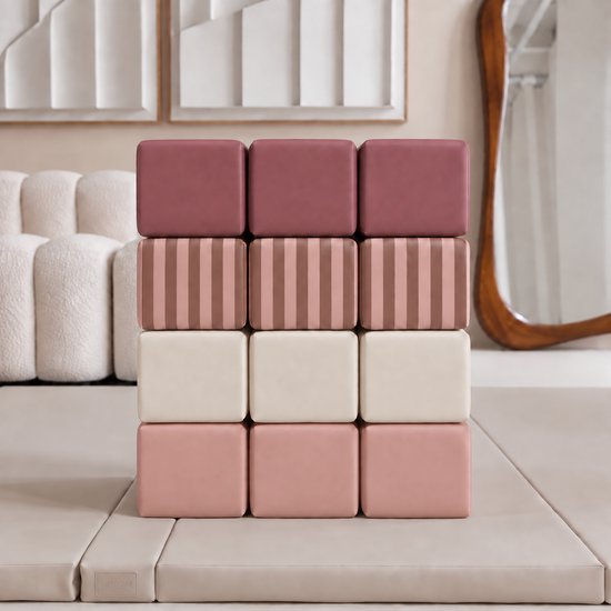 Stapelblokken in roze, crème en met bruine strepen. Een stapel van vier rijen met elk drie blokken, op een beige mat.