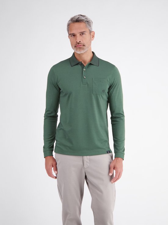 Man met lange mouwen, groen poloshirt met borstzakje, kraag met donkere bies en grijze broek.