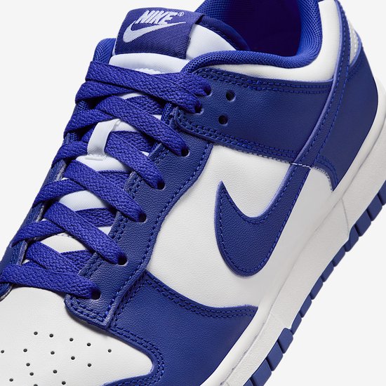 Close-up van de Nike Dunk Low in wit en blauw met Nike-logo op de tong.