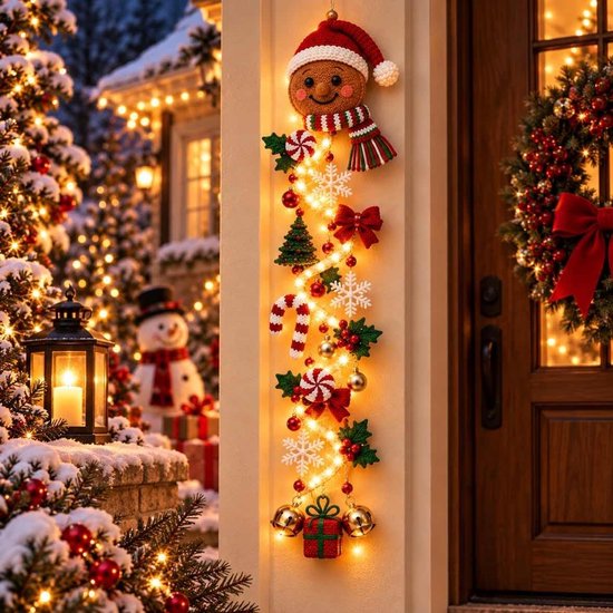 Gehaakte kersthanger met een peperkoekmannetje, LED-lichtjes, strikken, zuurstokjes en gouden klokjes bij een deur.