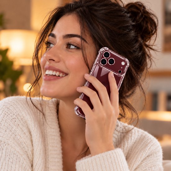 Vrouw met knotje belt met een bordeauxrood iPhone-hoesje met transparante, schokbestendige randen.