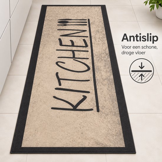 Antislip beige keukenmat met zwarte rand en 'KITCHEN' opdruk op een tegelvloer.