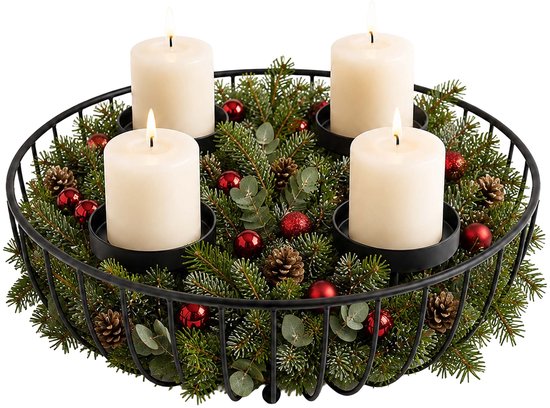 Zwarte metalen mand als adventskrans met dennentakken, rode kerstballen, dennenappels en vier brandende kaarsen.