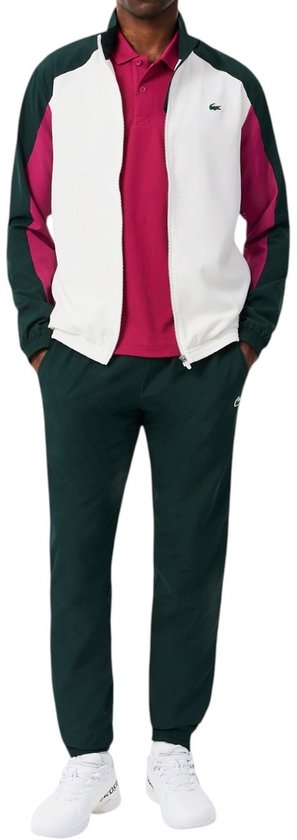 Man draagt een groen, wit en bordeaux trainingsjack met een witte broek en een rood poloshirt.