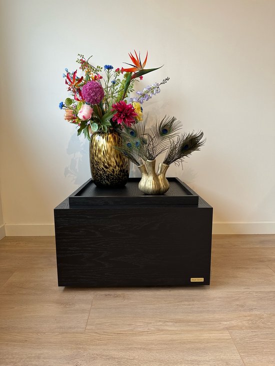 Zwart houten dienblad met een leopard print vaas met bloemen en pauwenveren.
