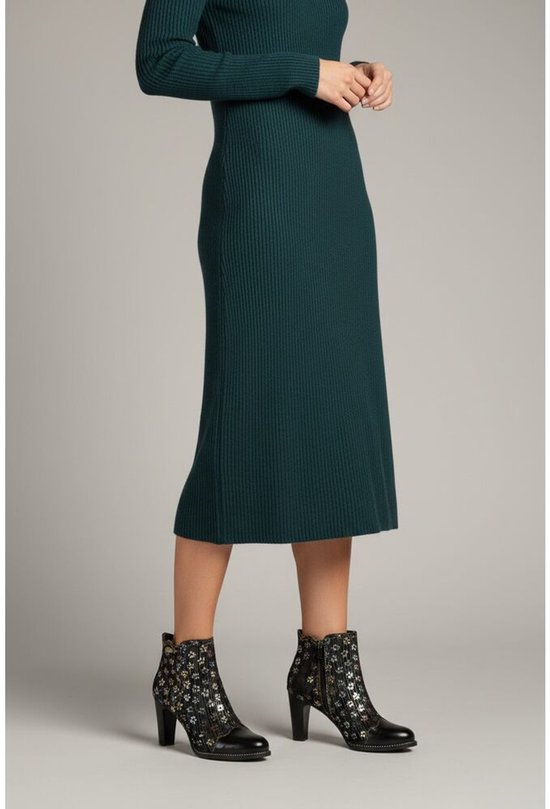 Model met donkergroene jurk en zwarte enkellaarzen met bloemenprint en hak.