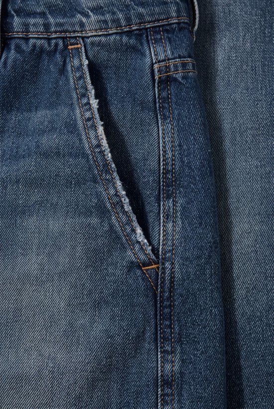 Detail van de rafelige zakopening van een donkerblauwe wijde jeans.