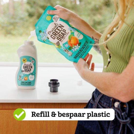 Hand vult een fles wasverzachter bij met een navulverpakking tegen plasticverspilling.