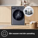 Lave-linge gris avec porte et panneau de commande noirs, à côté d'un panier de linge. À droite, une balance avec des piles de linge.