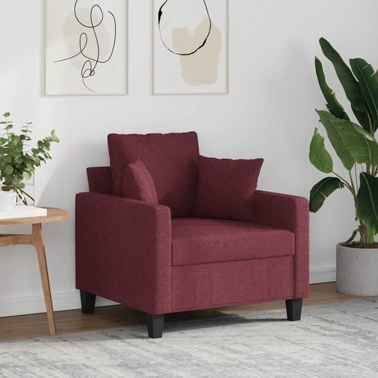Wijnrode fauteuil met losse kussens in een stijlvol ingerichte woonkamer.