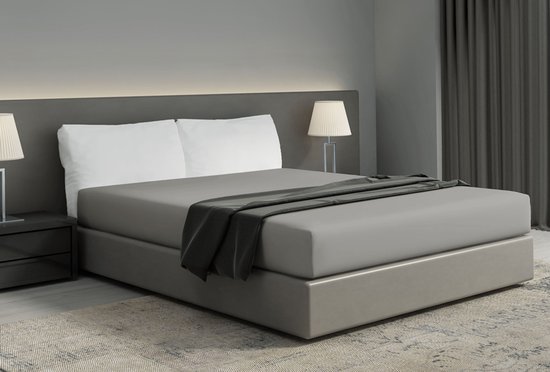 Un lit deux places avec un drap-housse gris, des oreillers blancs, un plaid gris foncé et des lampes de chaque côté.