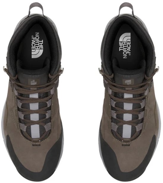 Bovenkant van bruine en zwarte mid-top wandelschoenen met veters en reflecterende details.