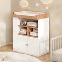 Witte commode met houten blad en aankleedkussen, geplaatst in een sfeervolle babykamer met sterren aan de muur.