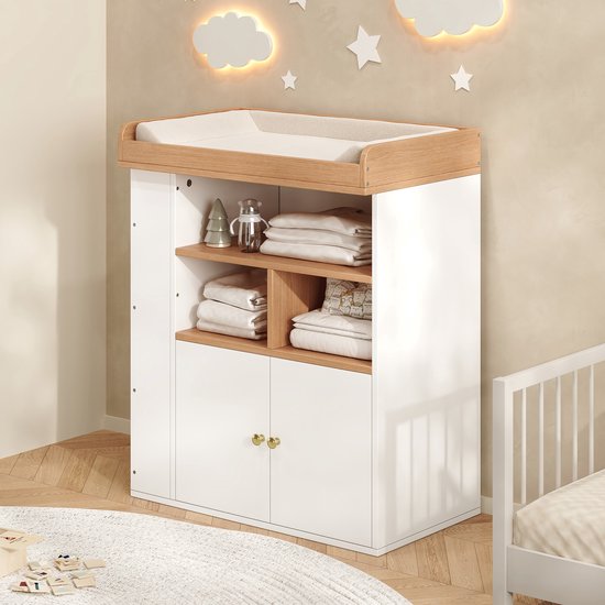 Witte commode met houten blad en aankleedkussen, geplaatst in een sfeervolle babykamer met sterren aan de muur.