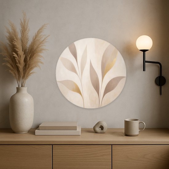 Detailopname van een ronde wandcirkel met abstracte, beige en goudkleurige bladeren boven een houten dressoir.