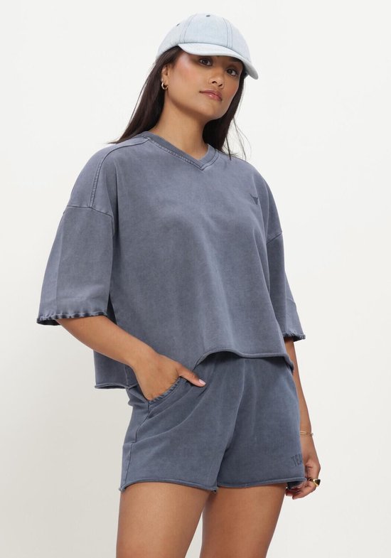 Blauw geknipte casual top met korte mouwen en een V-hals, gedragen door een model met een pet.