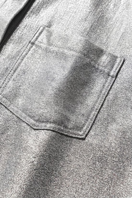 Detail van een zilverkleurige, glanzende borstzak op een blouse.