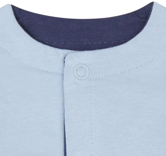 Detail van de sluiting van een lichtblauw vestje met donkerblauwe boord en knopen.