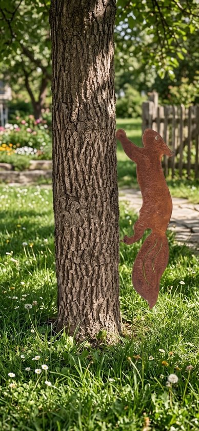 Roestige metalen eekhoorn bevestigd aan een boomstam in een tuin.