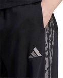 Close-up van het grijze adidas-logo op een zwarte joggingbroek met een luipaardprint detail.