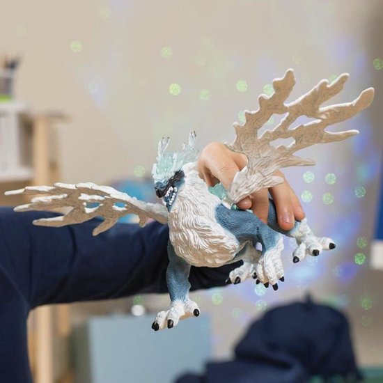 Een hand houdt een blauw-witte schildpadfiguur met witte vleugels en ijzige details vast.