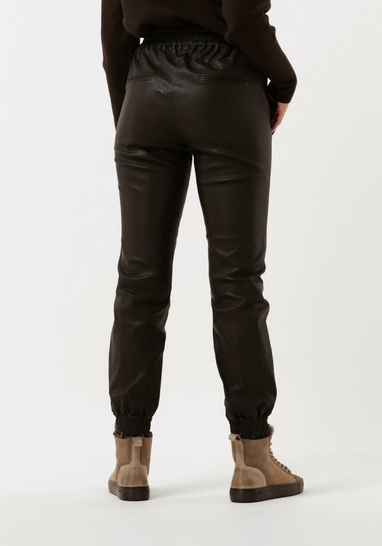 Achterkant van een vrouw in een donkerbruine leren broek met elastische tailleband en boorden.