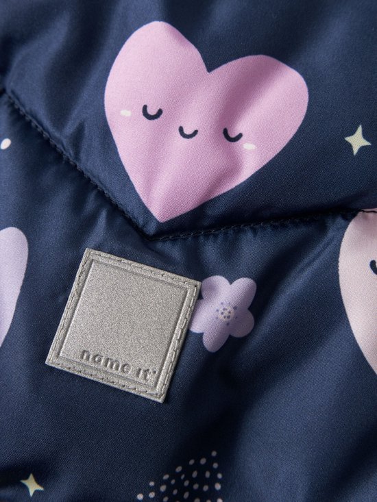 Close-up van het reflecterende vierkante name it-label op een donkerblauwe jas met roze hartjes.