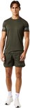 Man in een donkergroen sportshirt met logo op de mouwen en bijpassende donkergroene sportshort.