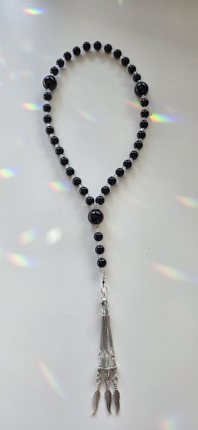 Zwarte agaat tasbih met kristallen accenten, eindigend in een zilveren kwastje met veerbedels op een witte achtergrond.