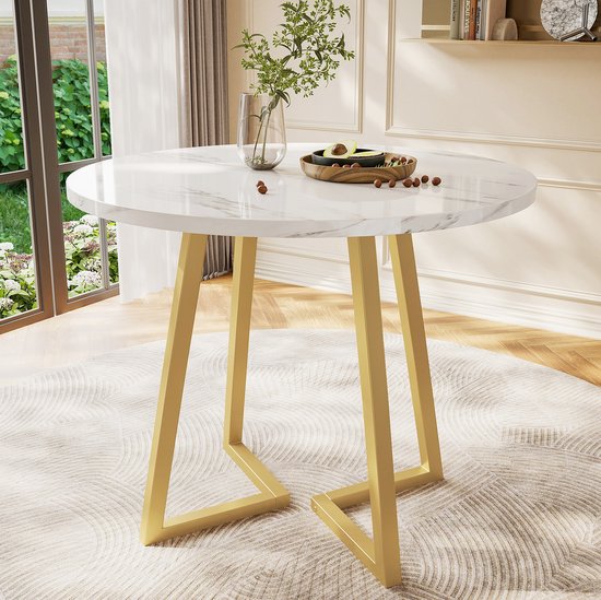 Ronde eettafel met wit marmerlook blad en opvallend goudkleurig geometrisch onderstel in een sfeervolle kamer.