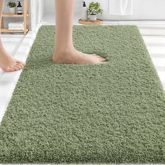 Voet op een zacht groene badmat met shaggy structuur.