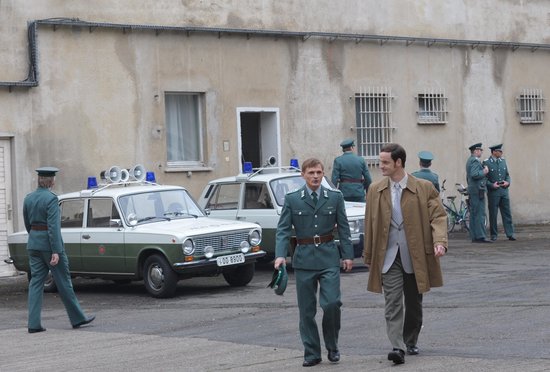 Twee mannen in een uniform lopen voorbij oldtimers met zwaailichten.