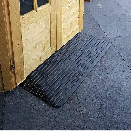 Zwarte rubberen drempelhulp met ribbelprofiel, voor een drempel van 25 mm hoog, naast een houten schuur.