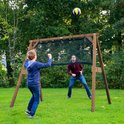 Jongen met tennisracket en bal voor een sportframe met volleybalnet, speler staat aan de andere kant.