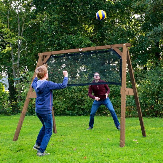 Jongen met tennisracket en bal voor een sportframe met volleybalnet, speler staat aan de andere kant.