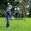 Jongen met tennisracket en bal voor een sportframe met net, speler staat aan de andere kant.