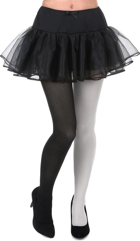 Tweekleurige panty met één zwart en één wit been, gedragen onder een zwart tule rokje en zwarte hakken.