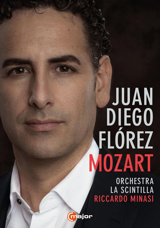 Close-up van Juan Diego Florez, een man met kort donker haar, die een zwart pak en een wit overhemd draagt.