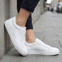 Dames die witte, leren sneakers dragen met veters en een witte zool.