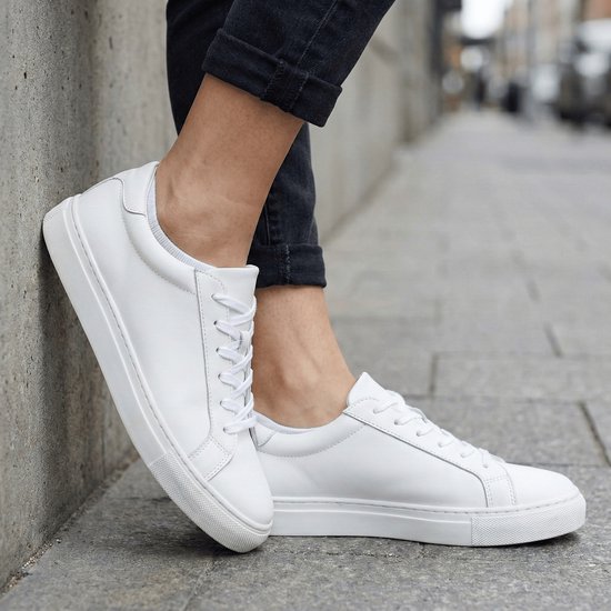 Dames die witte, leren sneakers dragen met veters en een witte zool.