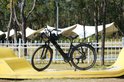 Zwarte elektrische fiets met bagagedrager en zwarte helm op het stuur, staand op een gele bocht.