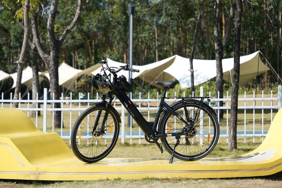 Zwarte elektrische fiets met bagagedrager en zwarte helm op het stuur, staand op een gele bocht.