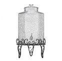 Transparante glazen drankdispenser met een getextureerd, facetglas oppervlak en een chromen kraan. Staat op een sierlijke zwarte metalen standaard.